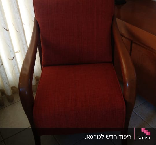 כורסה מרופדת בבד אדום עם ידיות עץ